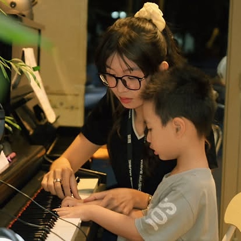 Giáo viên cùng học viên nhỏ tuổi tập piano
