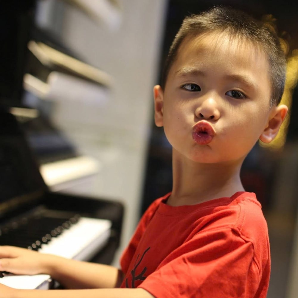 Bé tinh nghịch chu môi bên cây piano